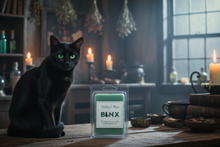 Load image into Gallery viewer, A black cat with glowing green eyes sits on a wooden table in a dimly lit, mystical room filled with candles, books, and potion bottles. In front of the cat is a small packaged product labeled 'BLNX'.
